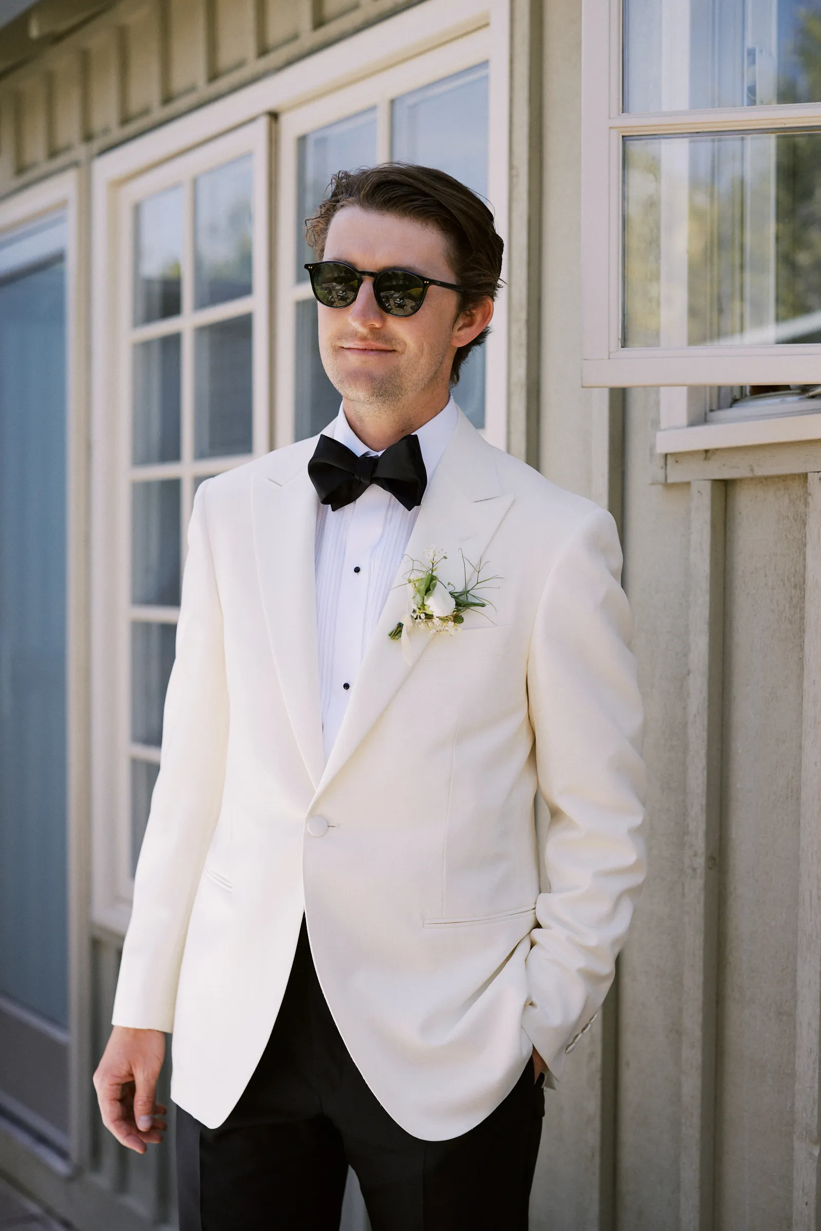 The groom in a white dinner jacket and sunglasses before the ceremony