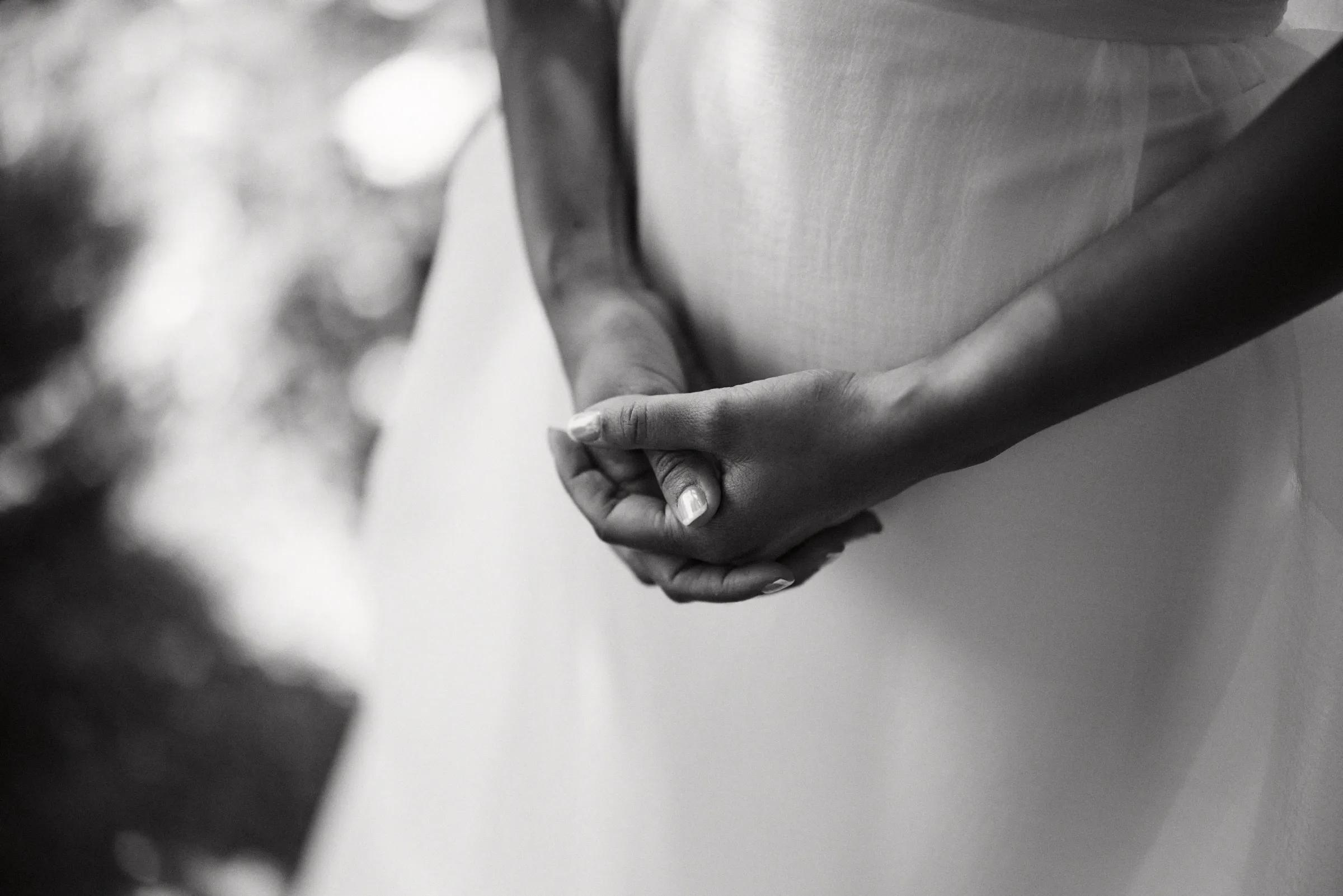 The bride's clasped hands against her dress, in black and white