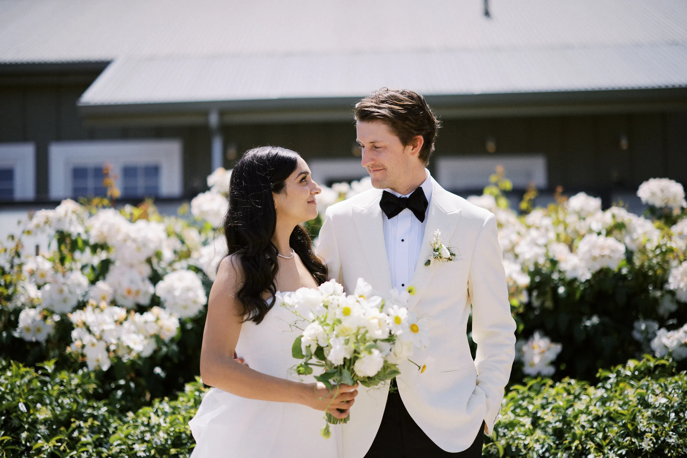 The couple beside a hedge of white roses