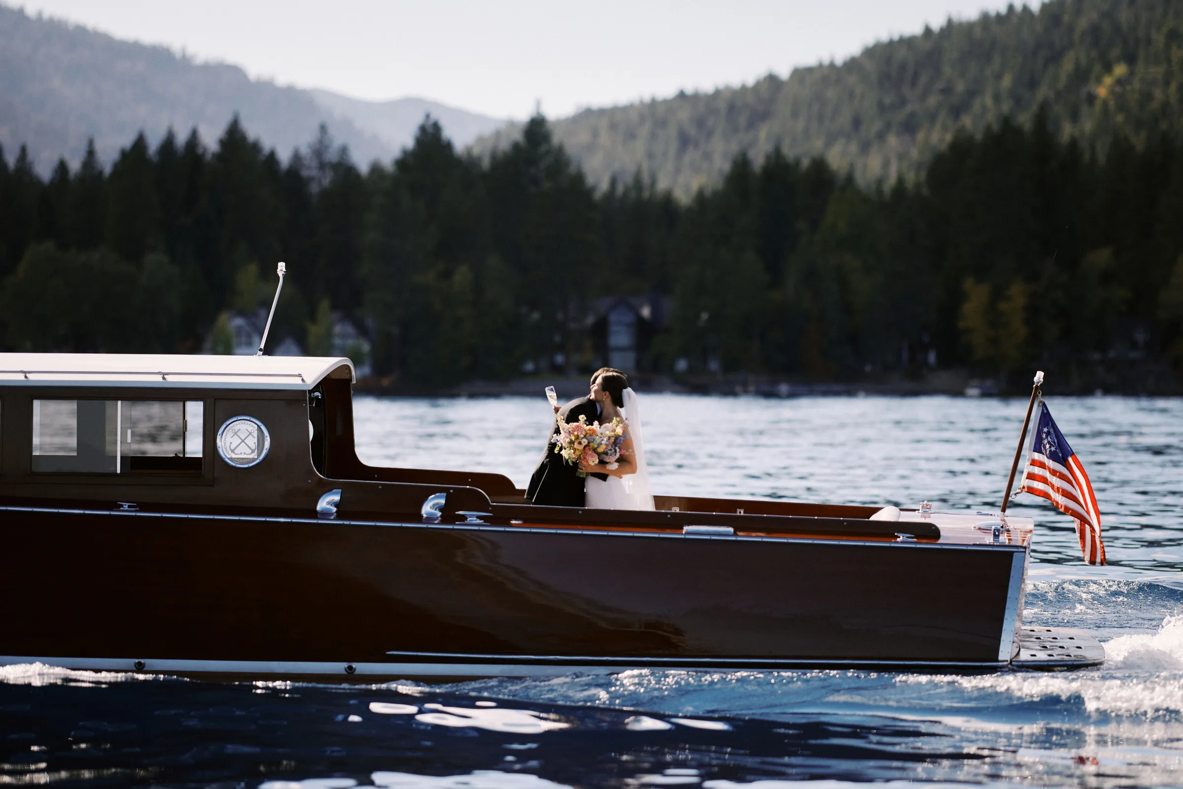 The couple kissing aboard a vintage wooden boat on Lake Tahoe